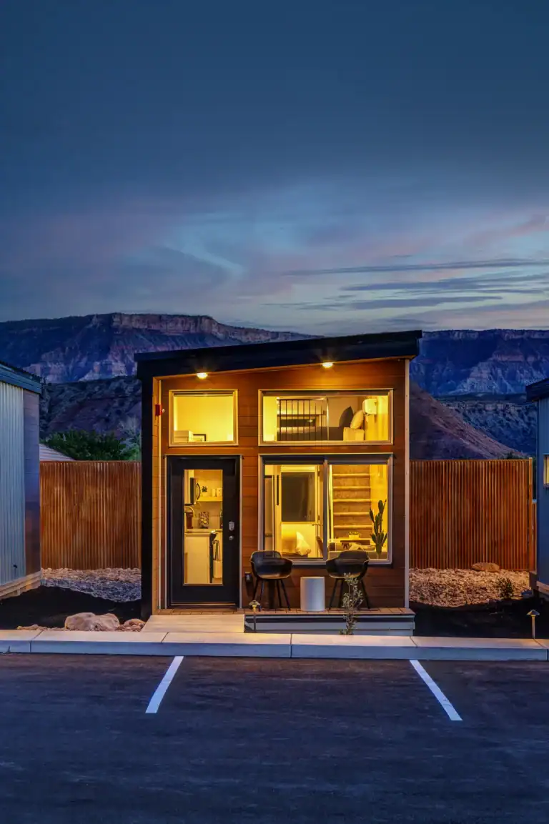 Contemporary Zip Kit modular home with large windows and outdoor seating at sunset.