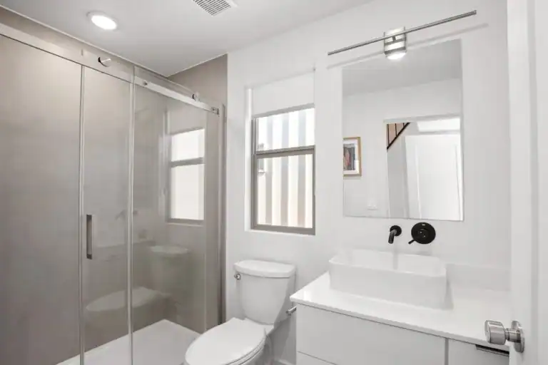 Bright modern bathroom with glass shower and white fixtures.