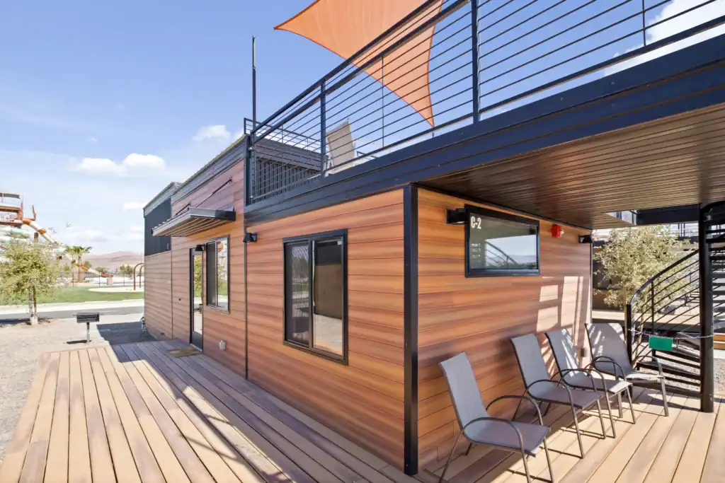 Contemporary modular home with wooden siding and outdoor seating area.