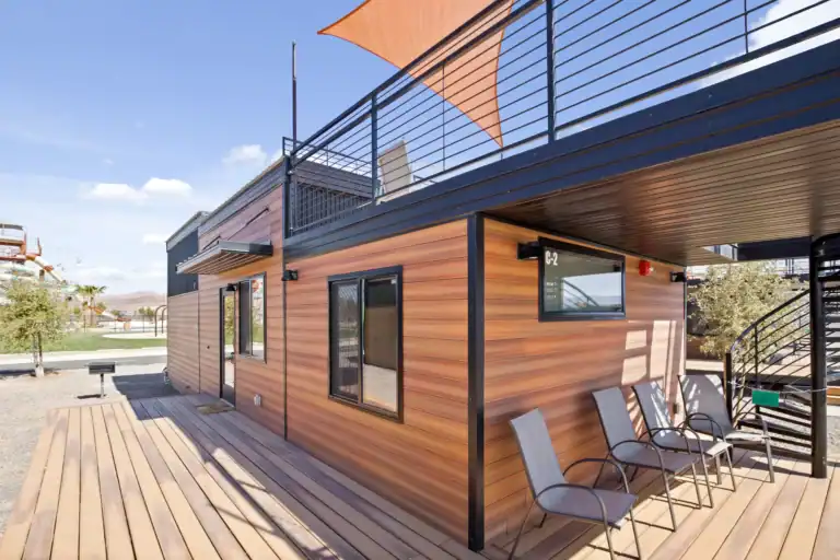 Contemporary modular home with wooden siding and outdoor seating area.