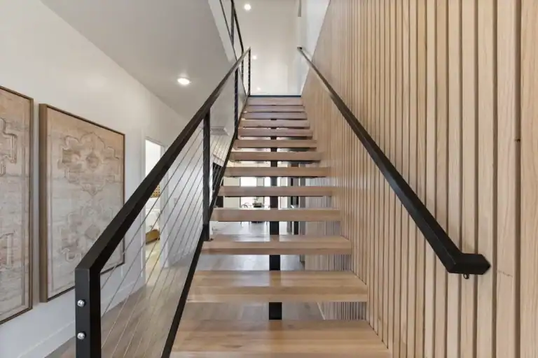 Contemporary staircase with wooden steps and black handrail inside Zip Kit Homes.