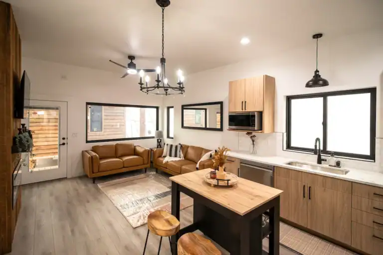 Modern interior of a tiny home with open living and kitchen area, natural light, and minimalist wood.