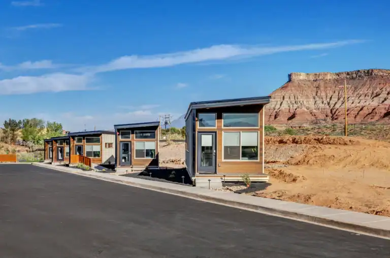 Contemporary modular homes on a paved street with desert landscape background.