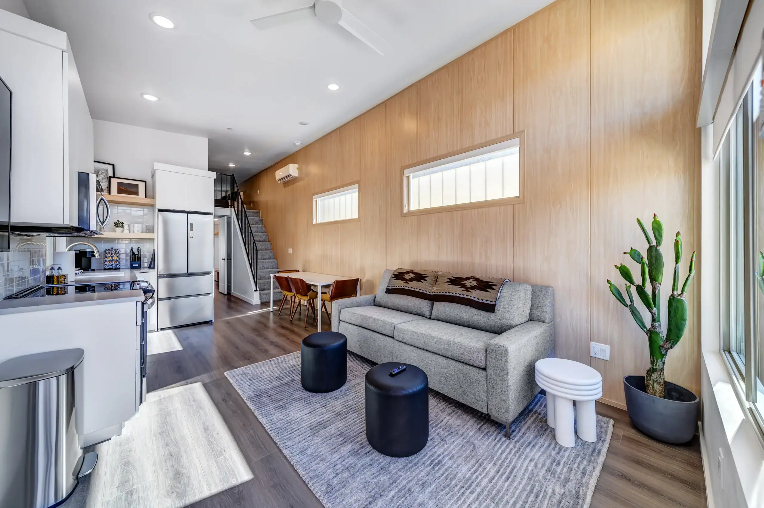 Bright living room with wooden wall, gray sofa, and large window.