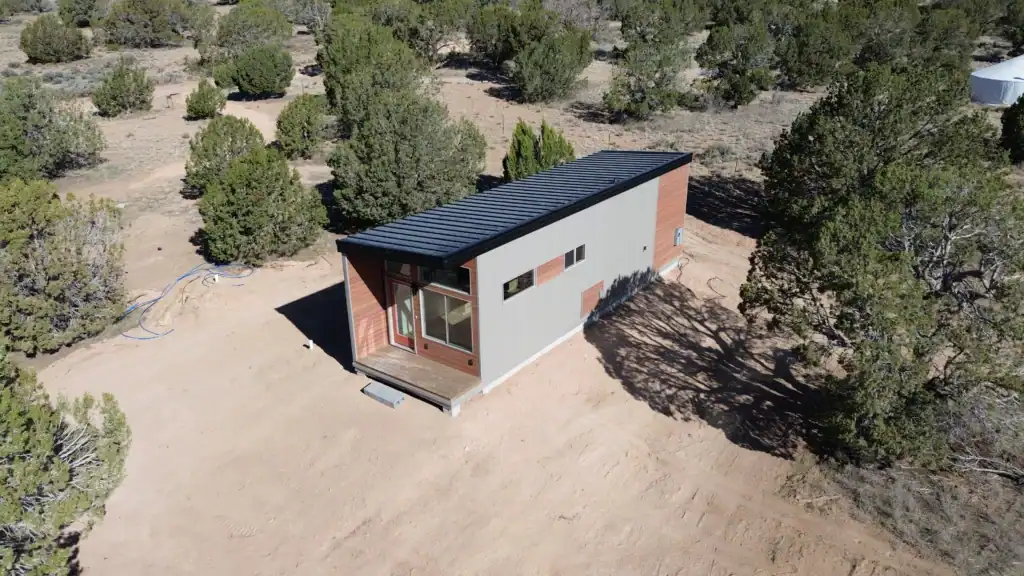 A modern Zip Kit home with a metal roof and large windows in a natural setting.