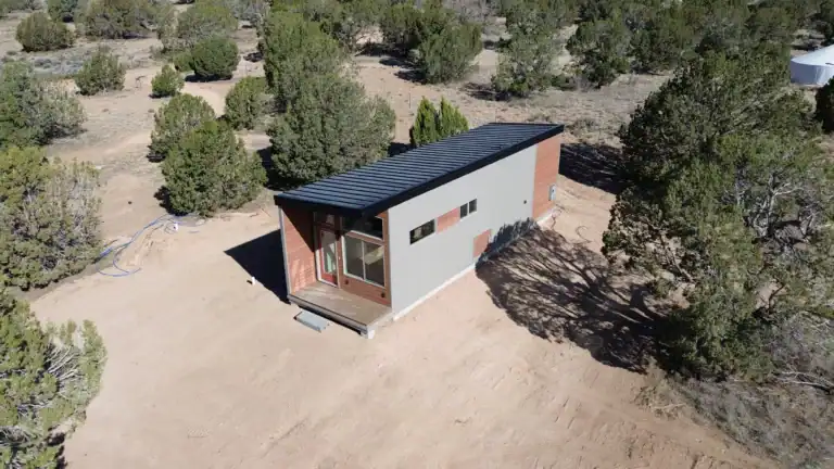 A modern Zip Kit home with a metal roof and large windows in a natural setting.
