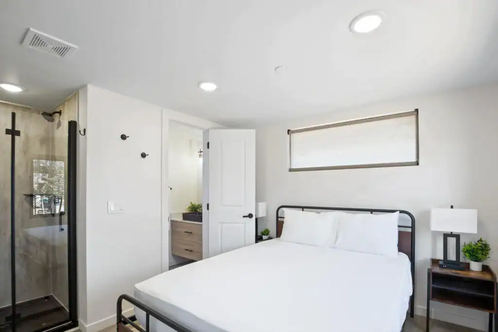 Bright bedroom with white walls, large window, and minimalist decor.