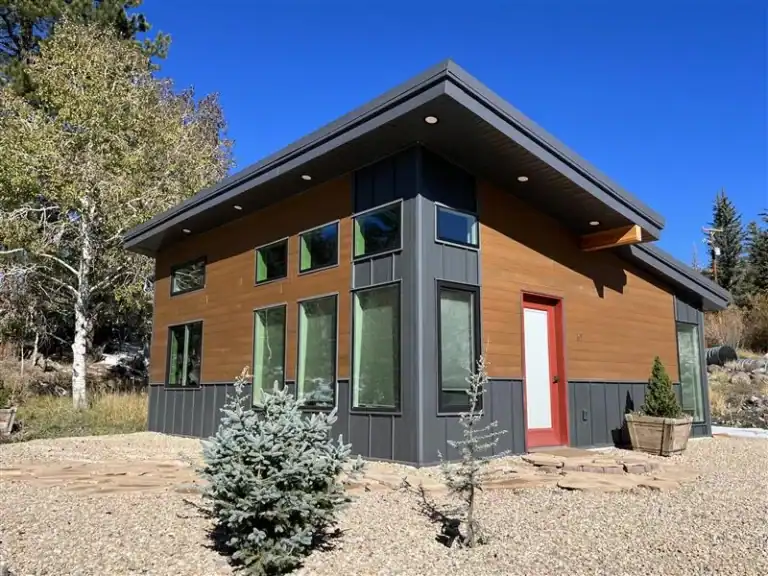 Big Sky floor plan by Zip Kit Homes, customizable modern home with wood siding and black accents set in a forested mountain landscape.