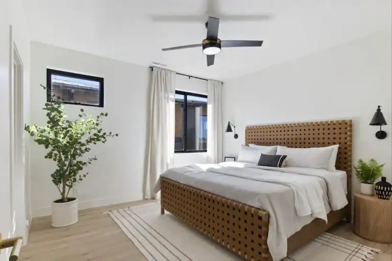 Bright modern bedroom with large windows, white walls, and minimalist decor.