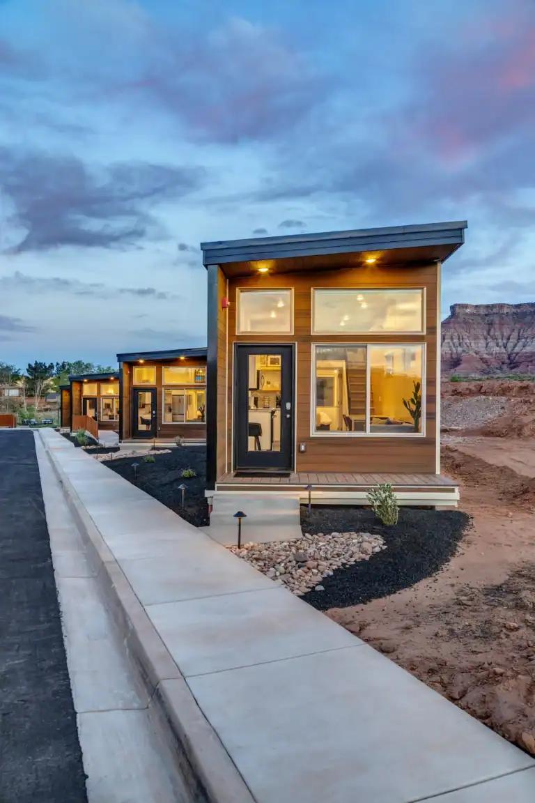 Contemporary Zip Kit Homes with large windows and outdoor seating at dusk.