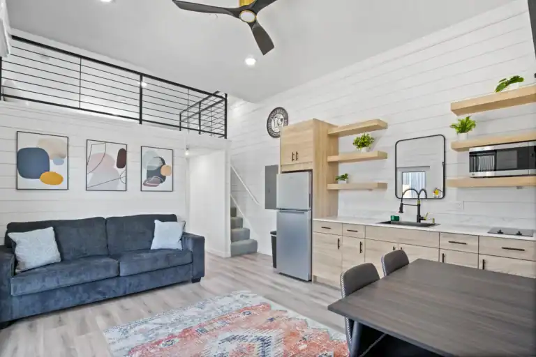 Open-concept tiny home with kitchen, living area, and loft space.