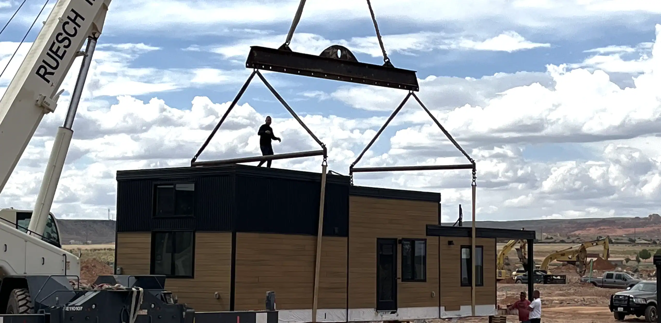 Crane lifting modular home section into place for construction.