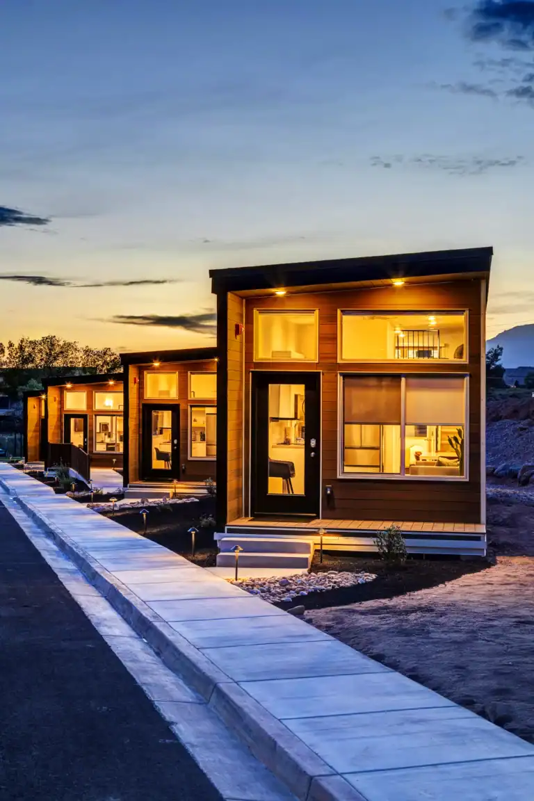 Contemporary modular homes with large windows and sleek design at sunset.