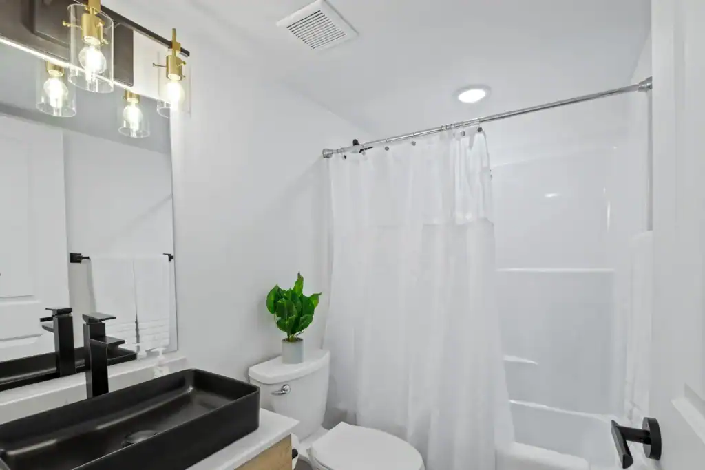 Contemporary bathroom with black sink, white walls, and shower curtain.