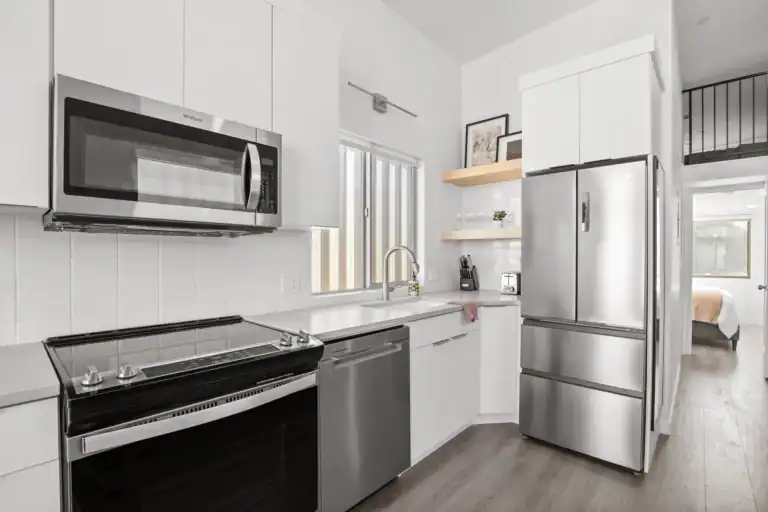 Contemporary modular kitchen with stainless steel appliances and white cabinetry.