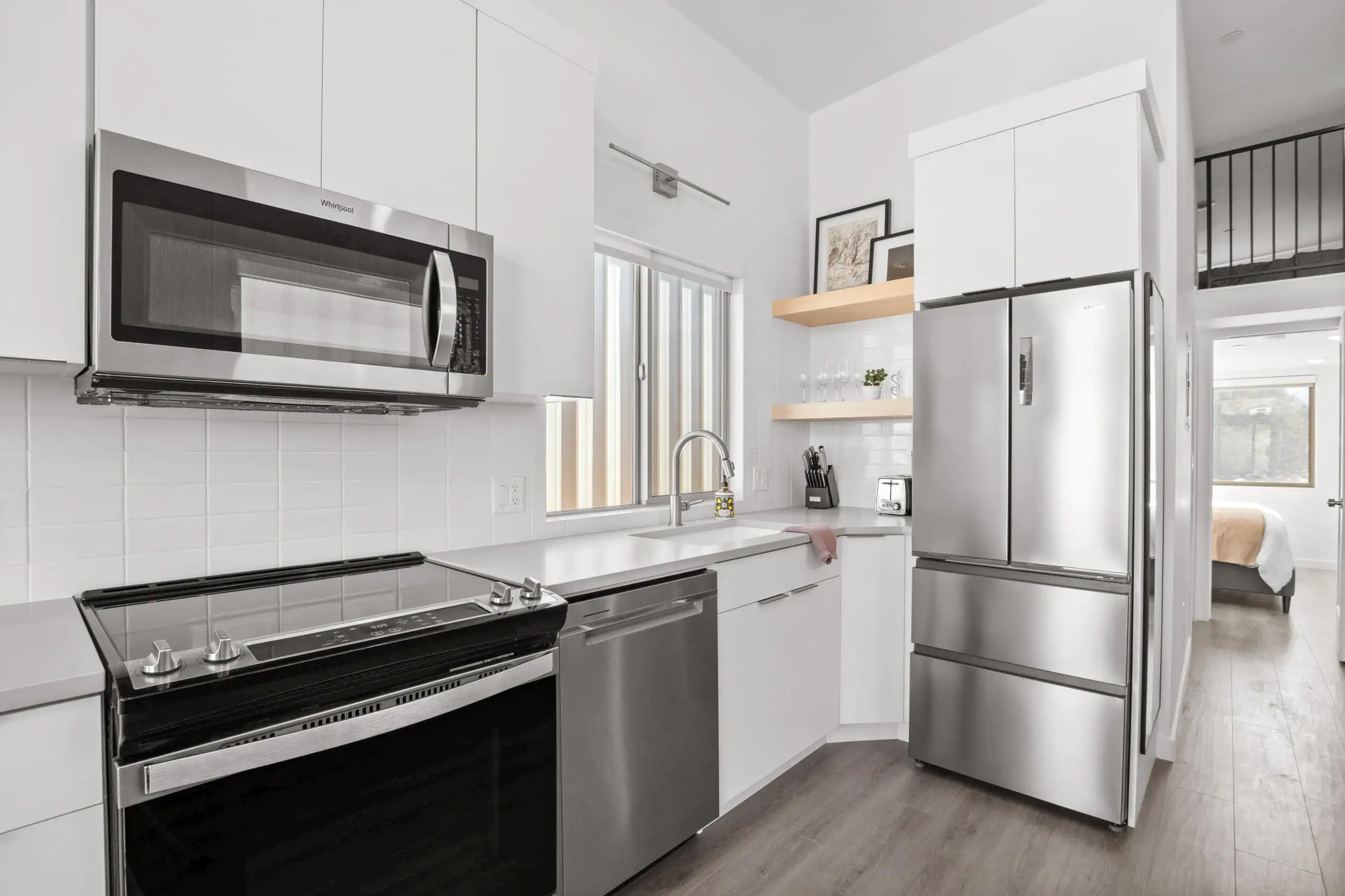 Contemporary modular kitchen with stainless steel appliances and white cabinetry.
