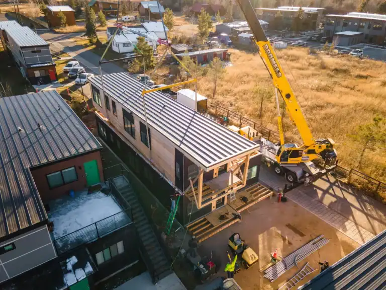 Construction of Zip Kit Homes with crane and workers on site.