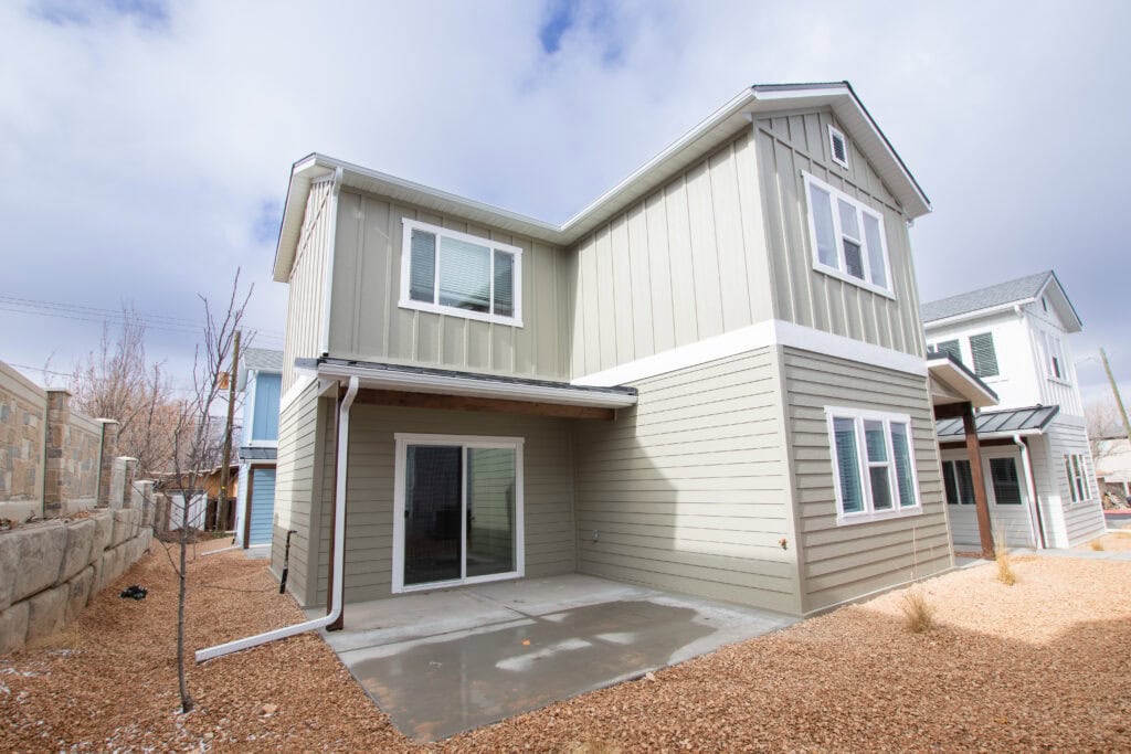 Modern tiny home with gray siding and large windows in a residential area.