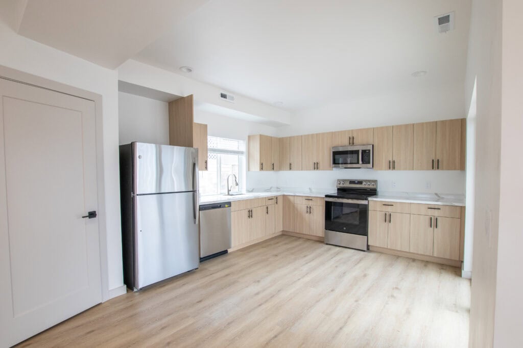 Modern Clyde tiny home kitchen with stainless steel appliances and light wood cabinets.