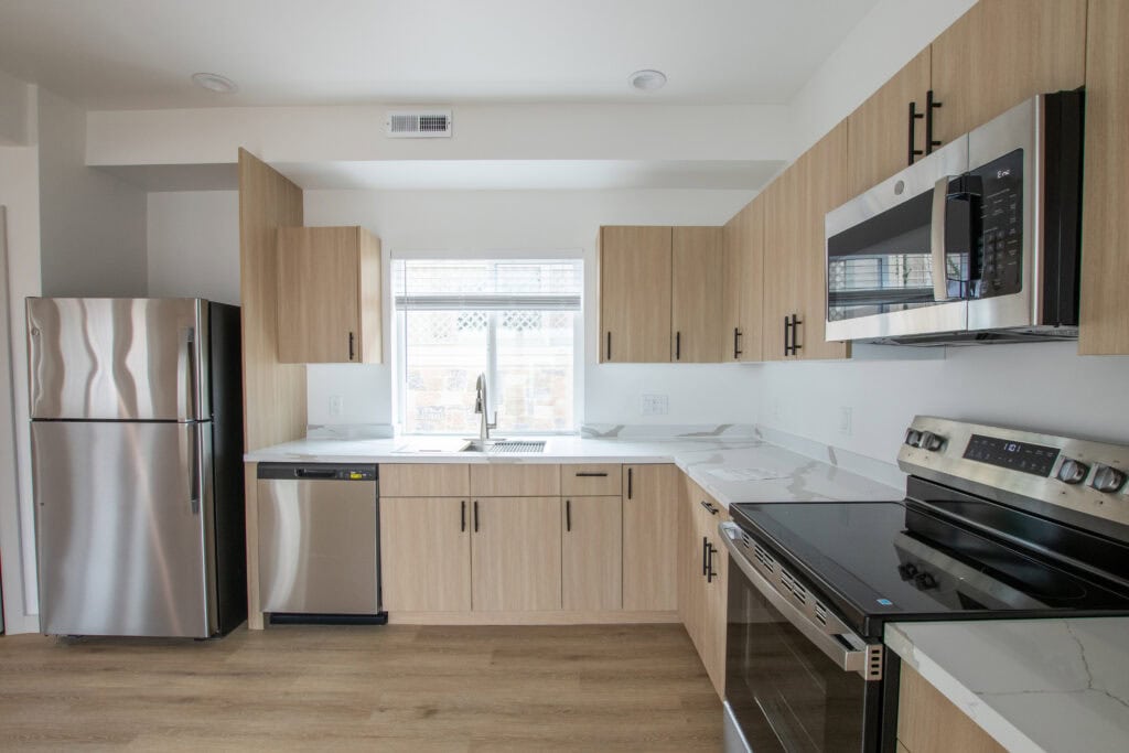 Contemporary Clyde tiny home kitchen with stainless steel appliances and light wood cabinets.