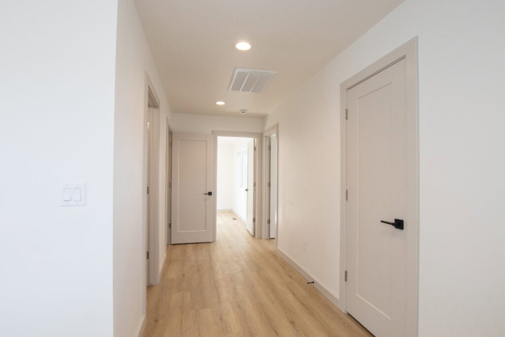 Bright hallway with white doors and light wood flooring in the Clyde model home.
