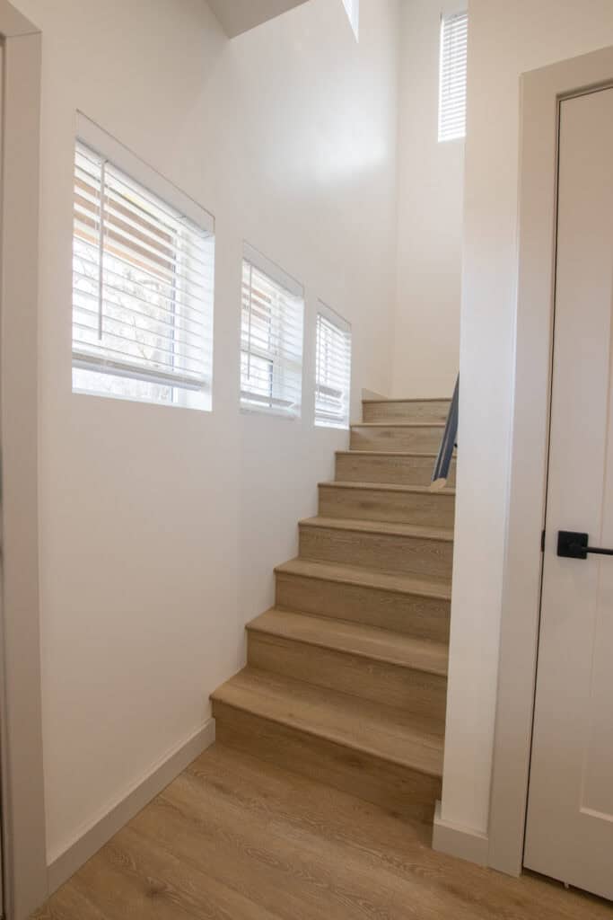 Modern interior staircase in Clyde tiny home with natural light and white walls.