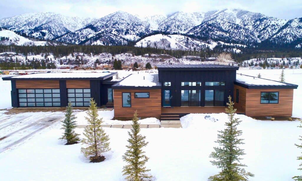 Alpine modern mountain home with wood siding, dark accents, and large windows.