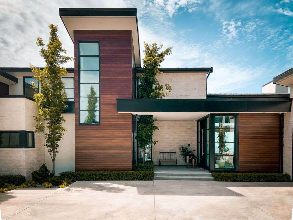 Custom modern home exterior with wood siding, large windows, and covered entry.