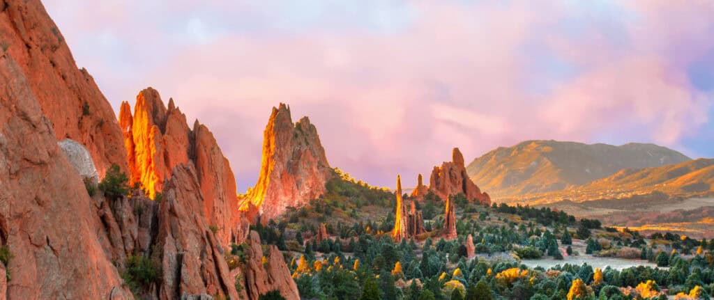 Scenic view of red rock formations and mountains at sunset in Colorado.