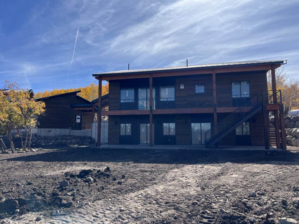 Moab home lower level exterior with covered patio under elevated deck.