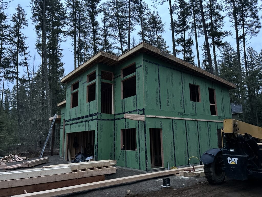 Koda panelized home kit under construction in Northern Idaho forest with modern two-story design and exposed framing.