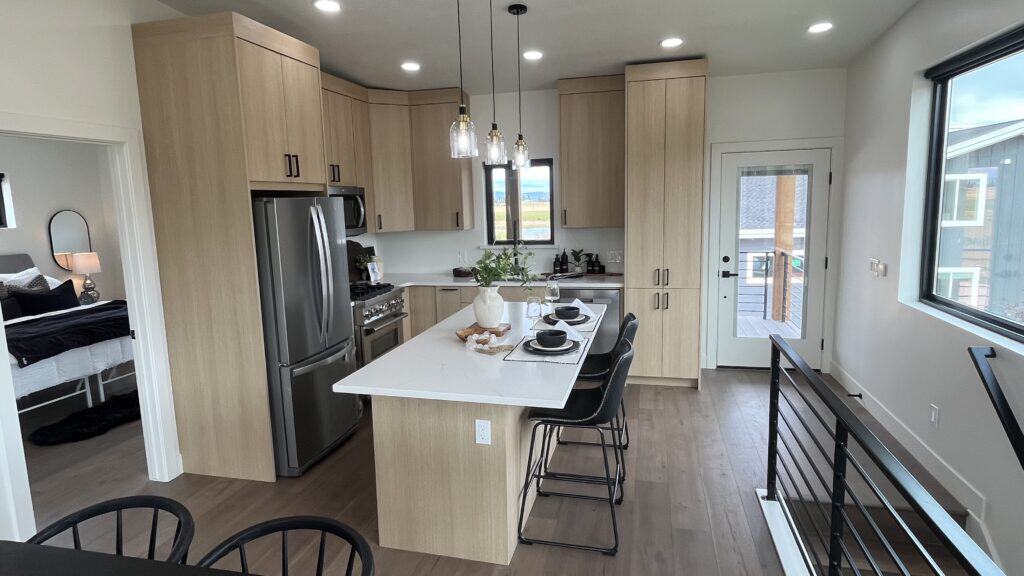 Bozeman interior kitchen with large island, light wood cabinetry, stainless steel appliances, and modern pendant lighting.