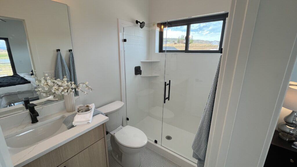 Bozeman bathroom with modern vanity, glass walk-in shower, and bright natural light from window.