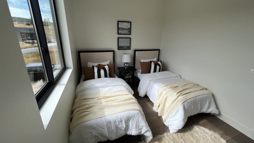 Bozeman bedroom with two twin beds, modern decor, and large window providing natural light.
