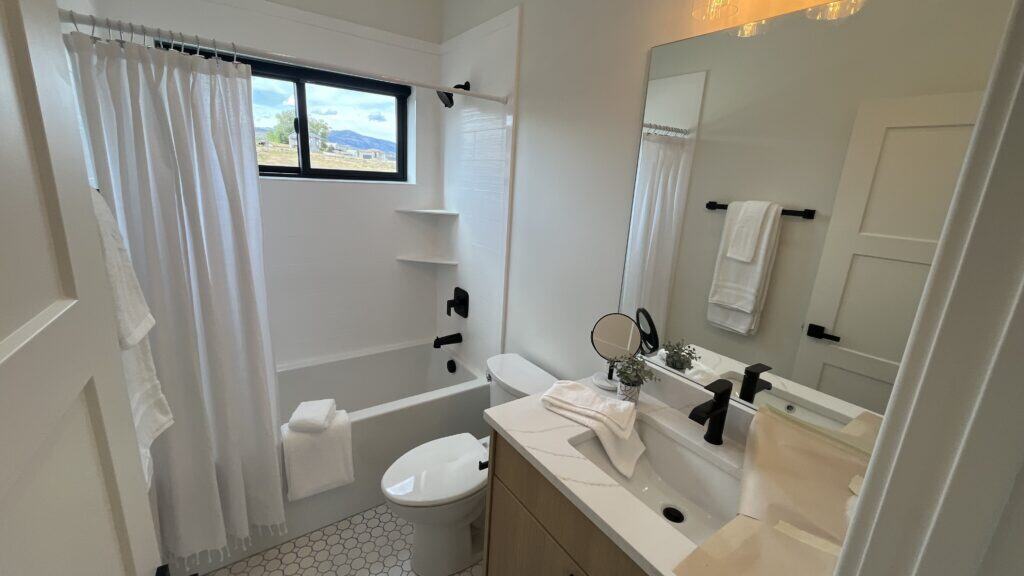 Bozeman bathroom with tub-shower combo, modern vanity, and large mirror with black fixtures.