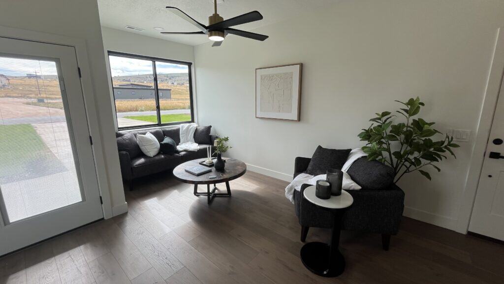 Bozeman living room with modern seating, wood flooring, and large window bringing in natural light.