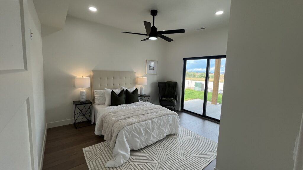 Bozeman primary bedroom with upholstered bed, bedside lamps, and sliding glass door to outdoor patio.
