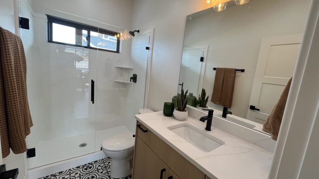 Bozeman bathroom with walk-in glass shower, modern vanity, and patterned tile flooring.