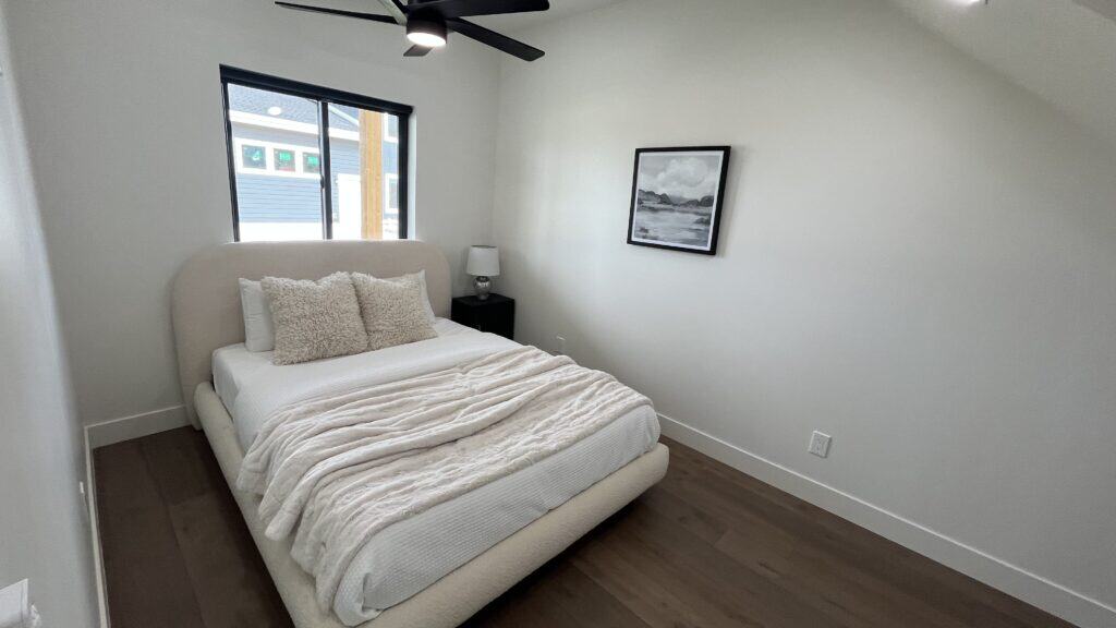 Bozeman bedroom with upholstered bed, neutral decor, and window providing natural light.
