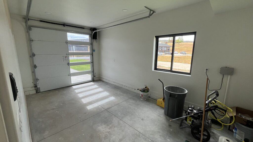 Bozeman one-car garage with concrete floor, window, and modern overhead door with glass panels.