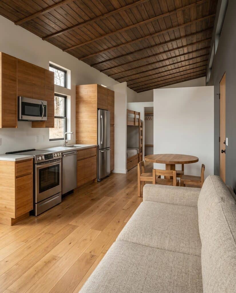 Koda downstairs studio with kitchen, dining table, and bunk beds under wood ceiling.