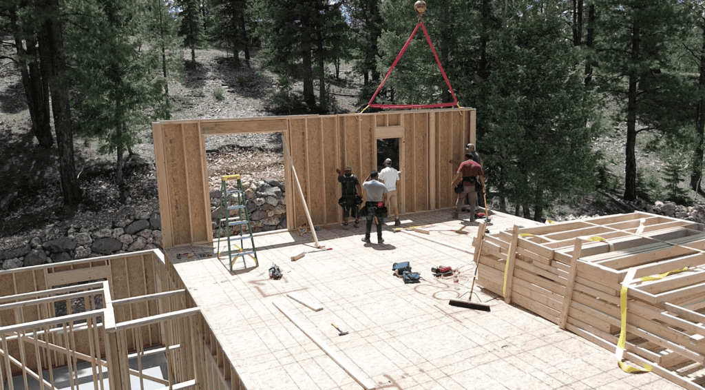 Modern Bozeman home under construction showing wall framing, open floor layout, and crew at work