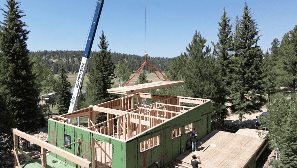 Bozeman house framing by Zip Kit Homes with crane placing roof section on structure