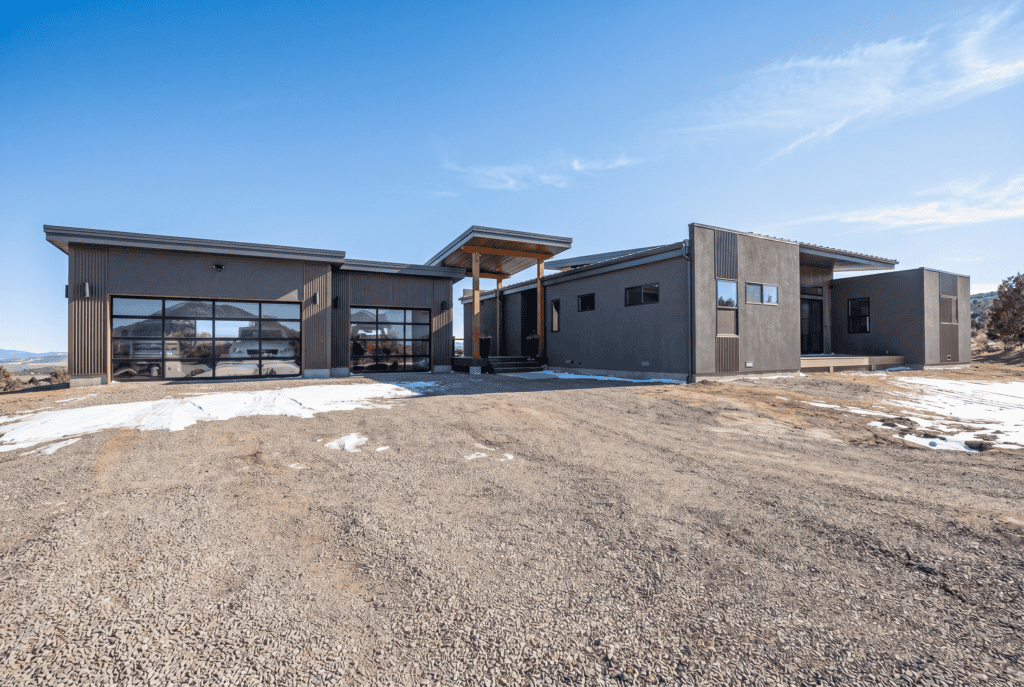Alpine front approach with multi-bay garage, glass garage doors, and covered breezeway entry at sunset.