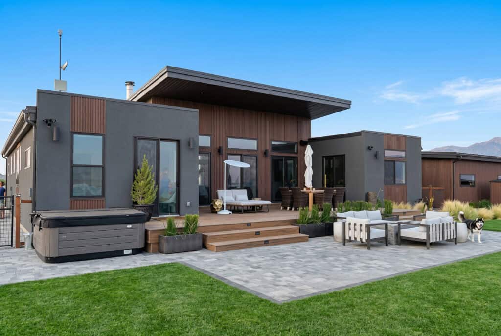 Alpine model modern mountain home rear exterior with large patio, expansive windows, and indoor-outdoor living by Zip Kit Homes.
