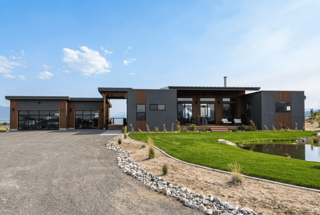 Alpine home angled front approach with driveway, breezeway entry, garage wing, and pond.