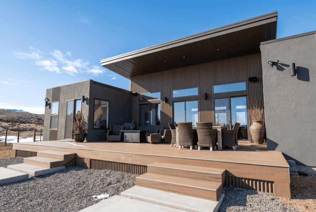 Alpine home rear patio with outdoor seating, dining area, and covered deck with wood siding detail.