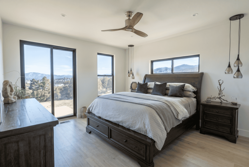 Modern bedroom with large windows and mountain views, minimalist decor, and wooden furniture.