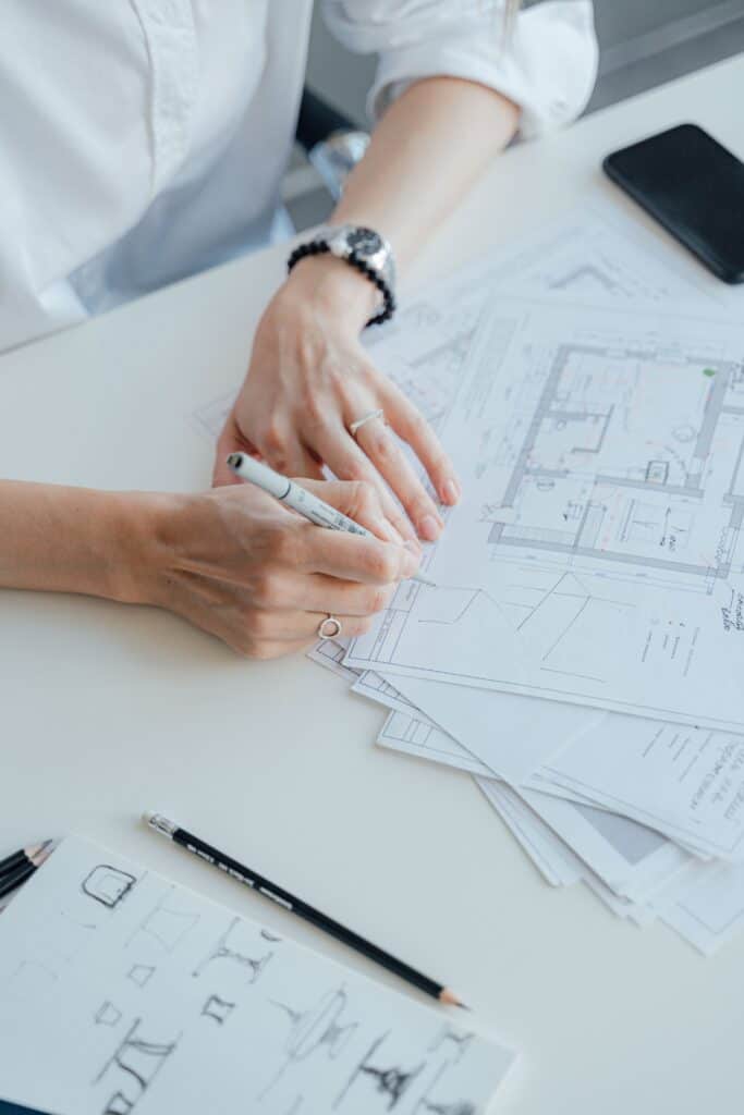 An architect writes notes on design plans while sitting at a desk, focusing on details.