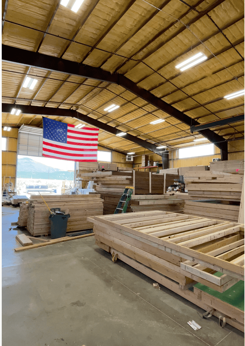 Wooden frames and materials in a spacious indoor workshop for Zip Kit Homes.